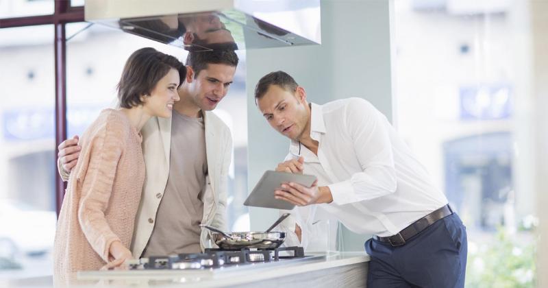 Hình ảnh một nhân viên bán lẻ đang nở nụ cười thân thiện và tận tình tư vấn cho khách hàng tại cửa hàng, thể hiện dịch vụ khách hàng xuất sắc và trải nghiệm mua sắm tích cực.